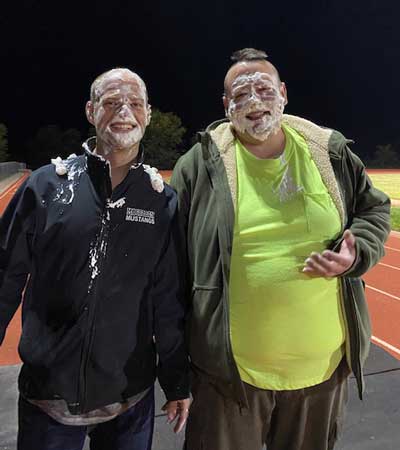 Two staff members with cream on their faces